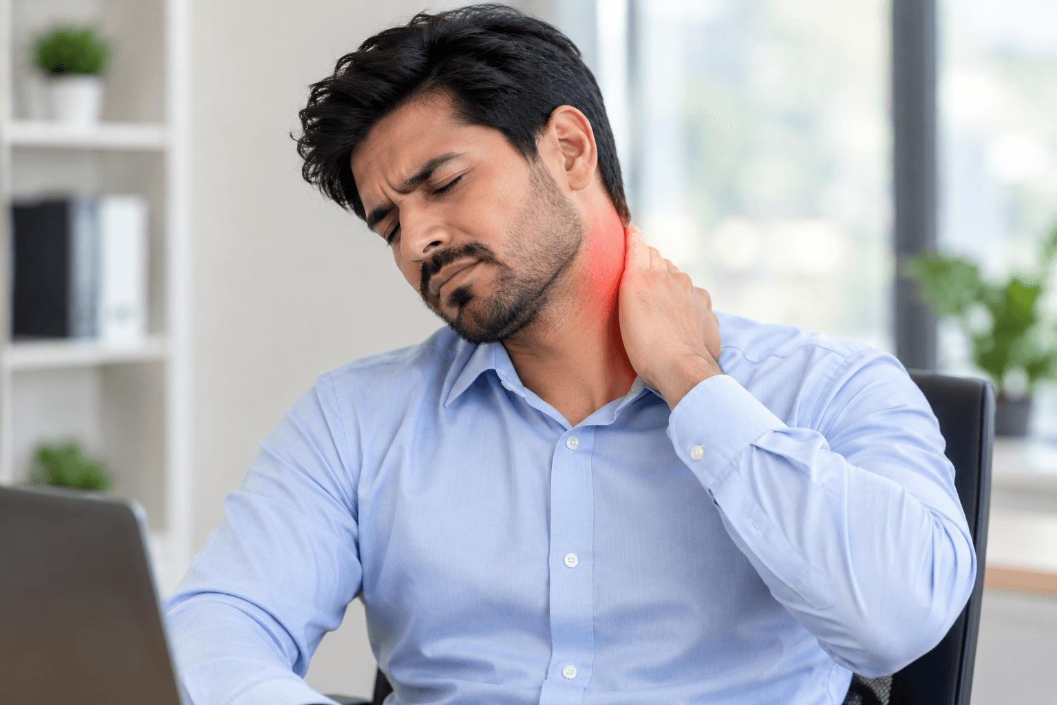 Man at a desk holding his neck in pain from chronic neck stiffness